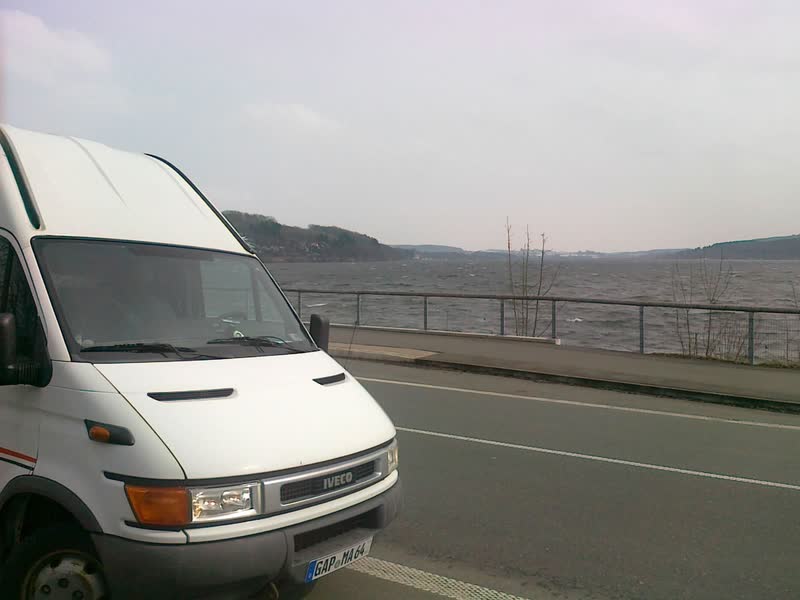 Weißer Transporter an einer Uferstraße am See